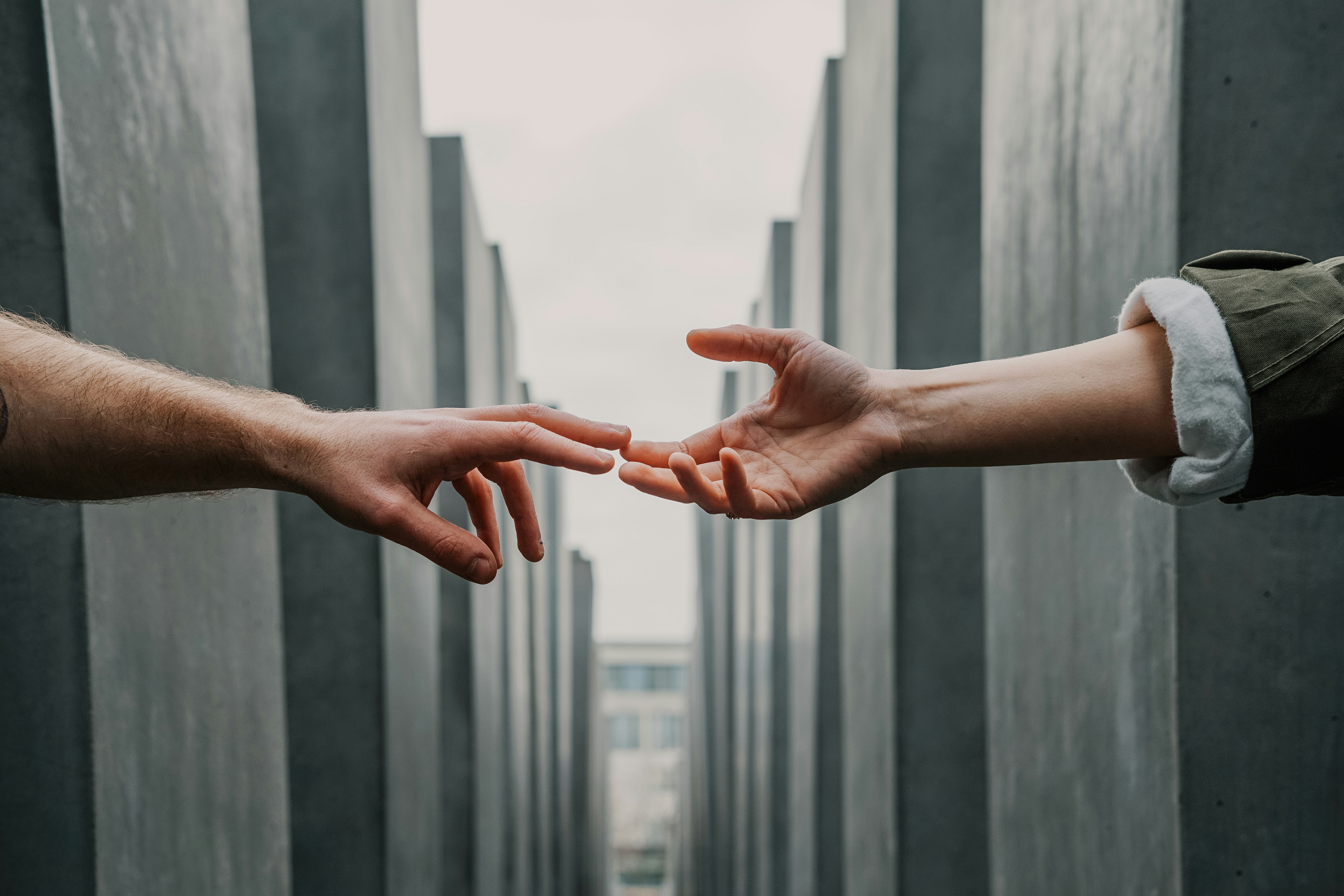 Image of two people grasping to hold hands at a distance, symbolizing the challenge of maintaining meaningful connections in the modern world.