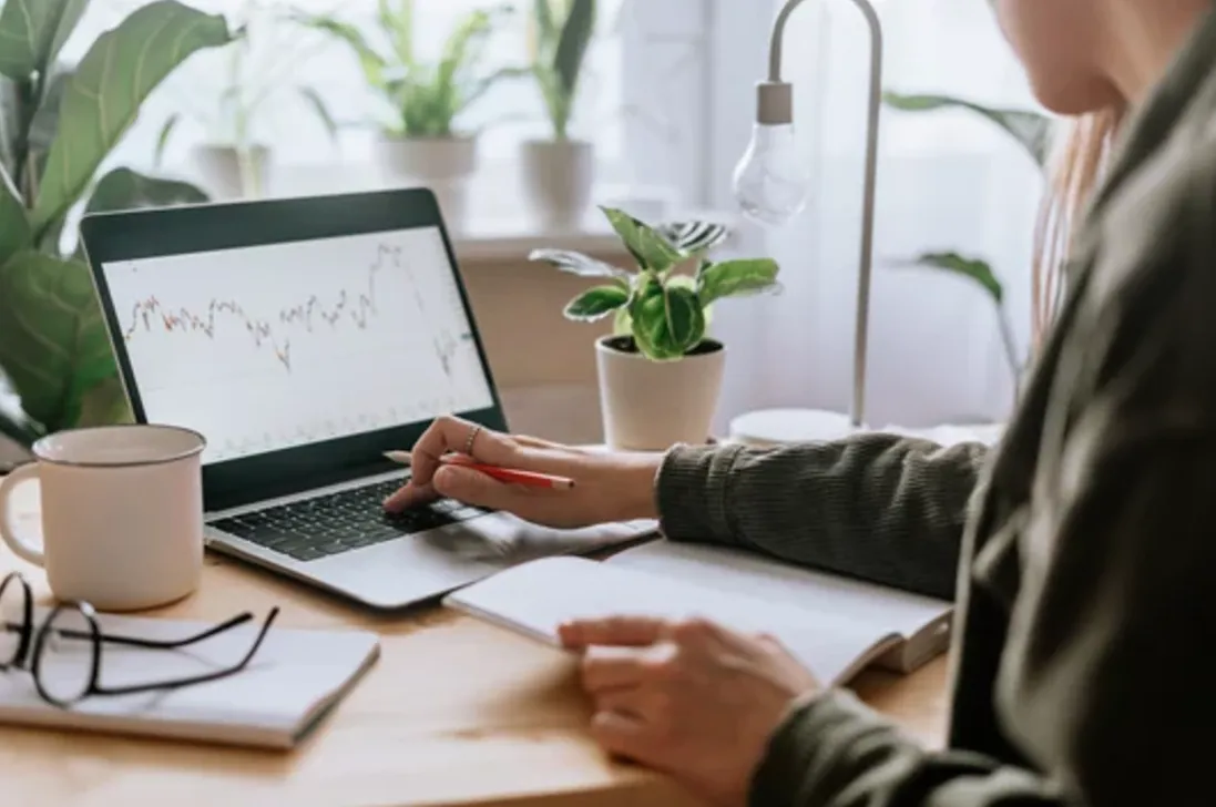 Image of person looking over their financial documents and a laptop, symbolizing the exploration of sustainable economic systems and personal finance.